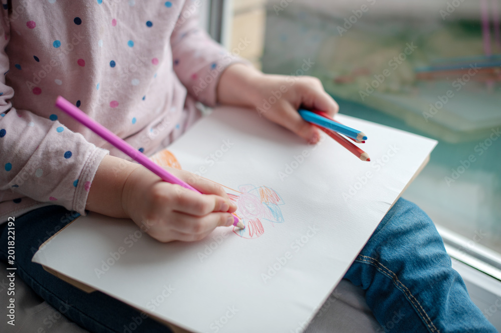 A child draws a flower with colored pencils A child draws a flower with colored pencils