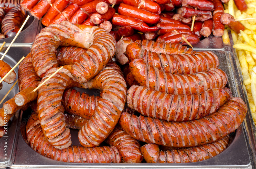 Fototapeta premium assorted sausages grilled on skewers on a large plate, mushrooms on the grill. Street festival food.