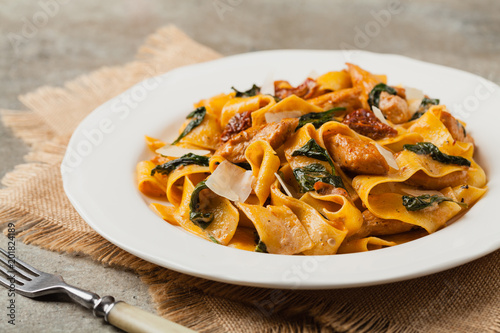 Italian salad, pappardelle pasta, with spinach, grilled chicken and dried tomatoes, sprinkled with flakes of cheese. photo