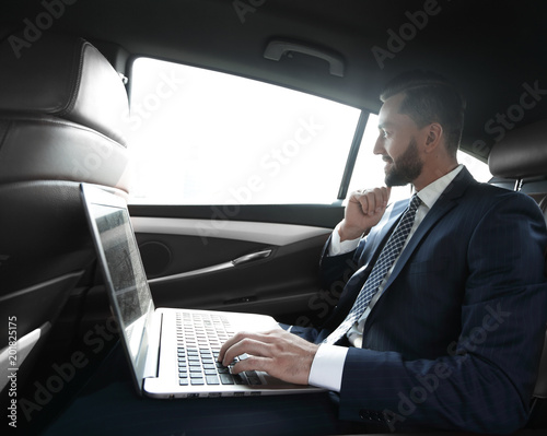 Businessman typing text on laptop while sitting in car © ASDF