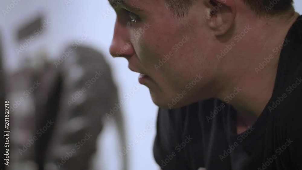 Slow motion close up of a young MMA fighter in deep focus during a training session and then looks up at something off camera Slow motion close up of a young MMA fighter in deep focus during a training session and then looks up at something off camera