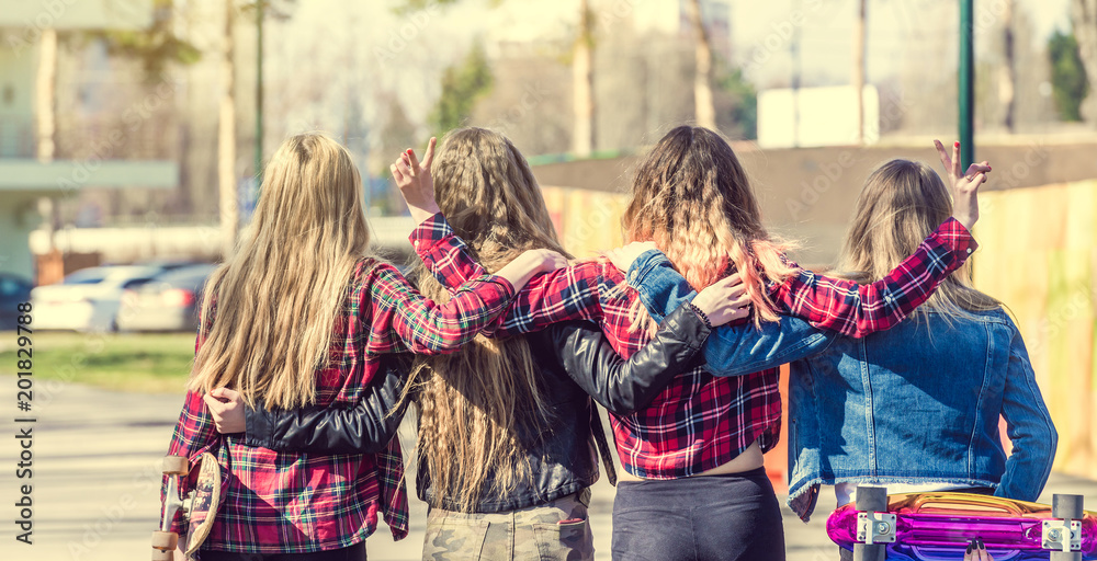 Obraz premium Back view of four girl friends hugging