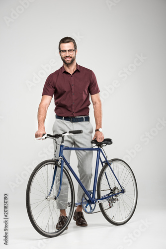 elegant smiling man posing with bicycle, isolated on grey