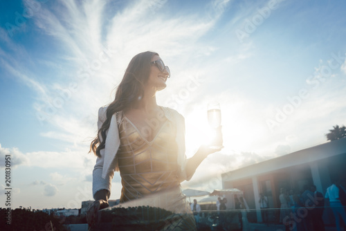 Canvas Print Woman having champagne at summer party with villa in the background