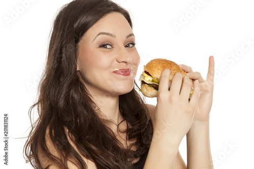 young stuffed greedy woman eating a hamburger on white background