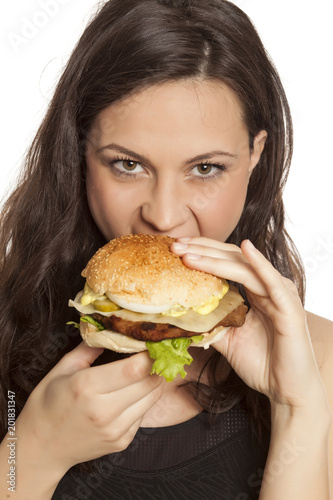 young beautiful greedy woman eating a hamburger on white background