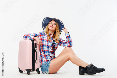Portrait of woman in hat sitting near suitcase