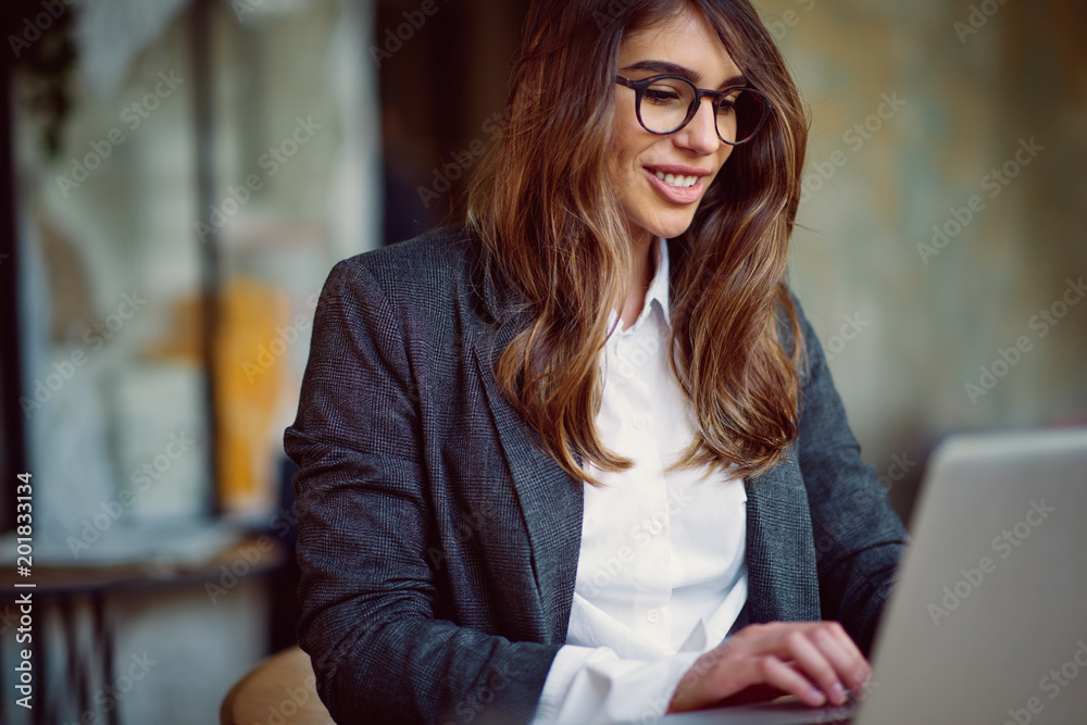 Young modern woman sitting in cafe and using laptop.