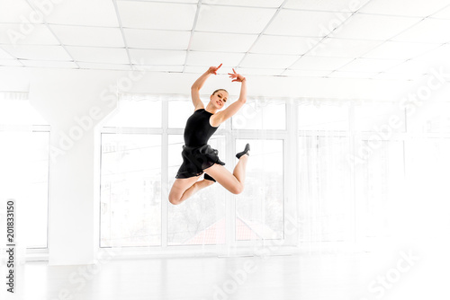 Ballerina dancer performing a jump in white studio