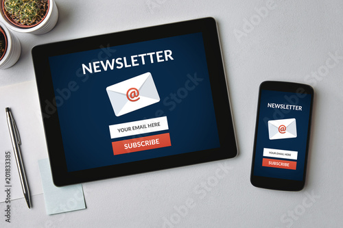 Subscribe newsletter concept on tablet and smartphone screen over gray table. All screen content is designed by me. Flat lay