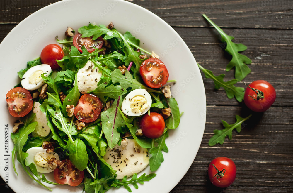 Fresh salad with tomatoes, mixed greens ,nuts, eggs, on wooden background . Healthy food. Fresh salad with tomatoes, mixed greens ,nuts, eggs, on wooden background . Healthy food.