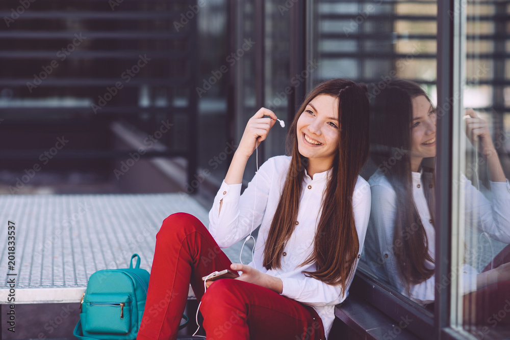 Fototapeta premium A teenage girl with a smartphone in her hands spends time outdoors
