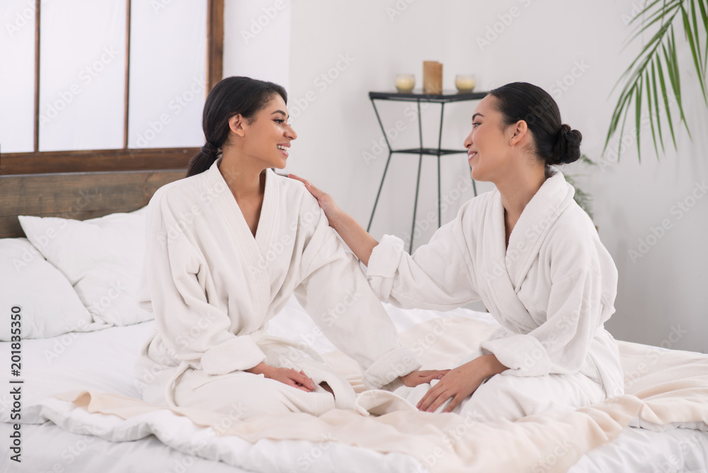 Lesbian partners. Happy attractive woman looking at her partner while being in the spa salon together with her
