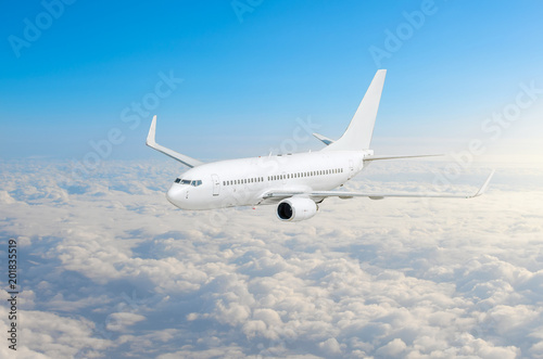 Passenger airplane fly on a hight above clouds and blue sky.
