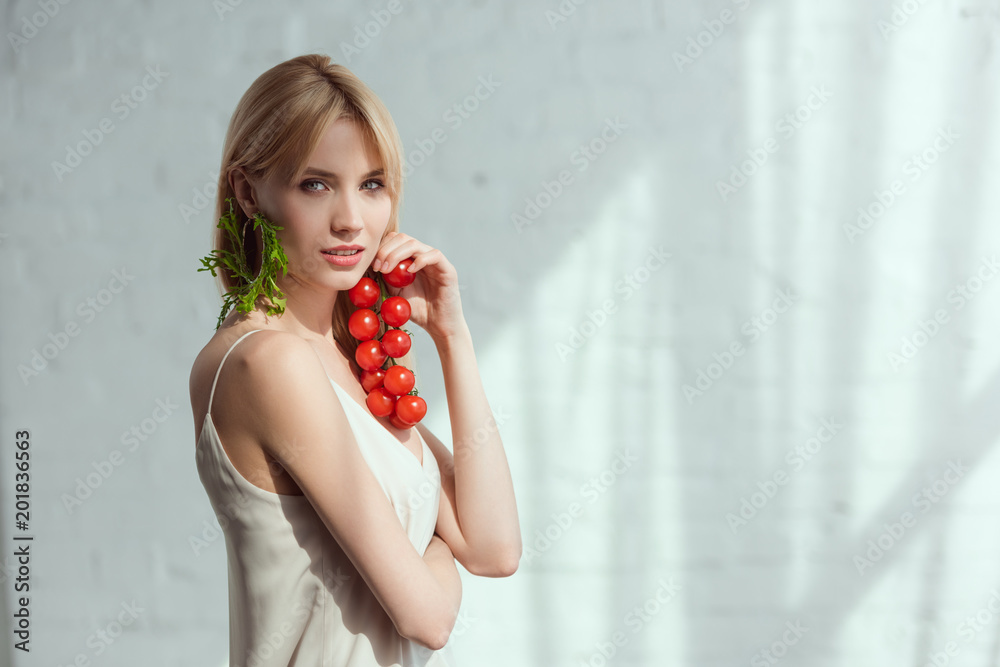young woman with cherry tomatoes in hand and earring made of fresh arugula, vegan lifestyle concept young woman with cherry tomatoes in hand and earring made of fresh arugula, vegan lifestyle concept
