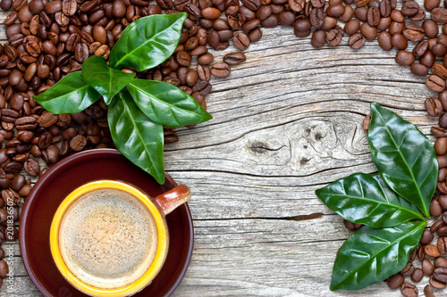 Cup of coffee with fresh coffee leaves on coffee beans background