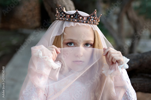 a young concubine princess in the crown covers her face with a veil and looks reproachfully photo