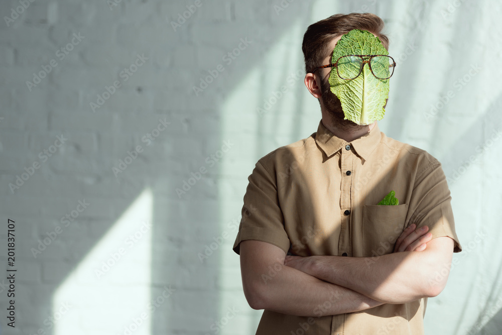 obscured view of man with savoy cabbage leaf and eyeglasses on face, vegan lifestyle concept - obrazy, fototapety, plakaty 