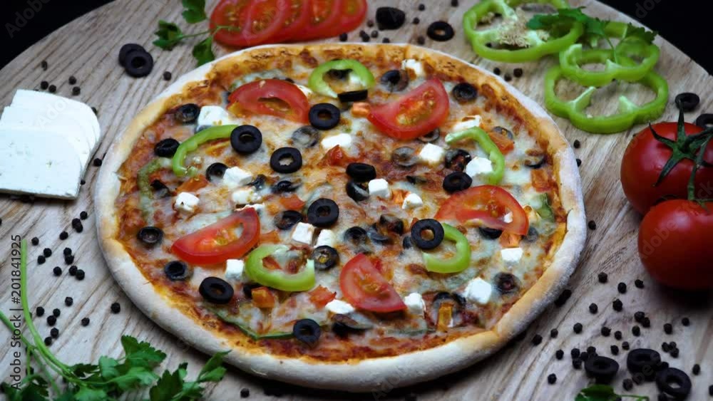 Rotating vegetable pizza with minced meat on a wooden stand isolated on a black background. 4K Rotating vegetable pizza with minced meat on a wooden stand isolated on a black background. 4K