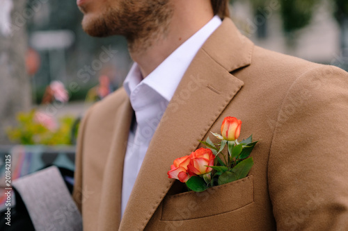 Close-up man dressed in classy jaket with three roses in poket photo