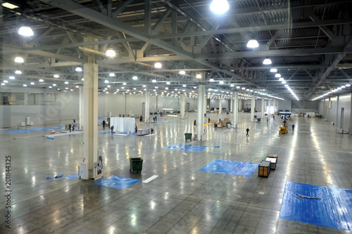 Large empty warehouse interior in an industrial building with high vertical columns with and high ceiling and artificial lighting horizontal view photo