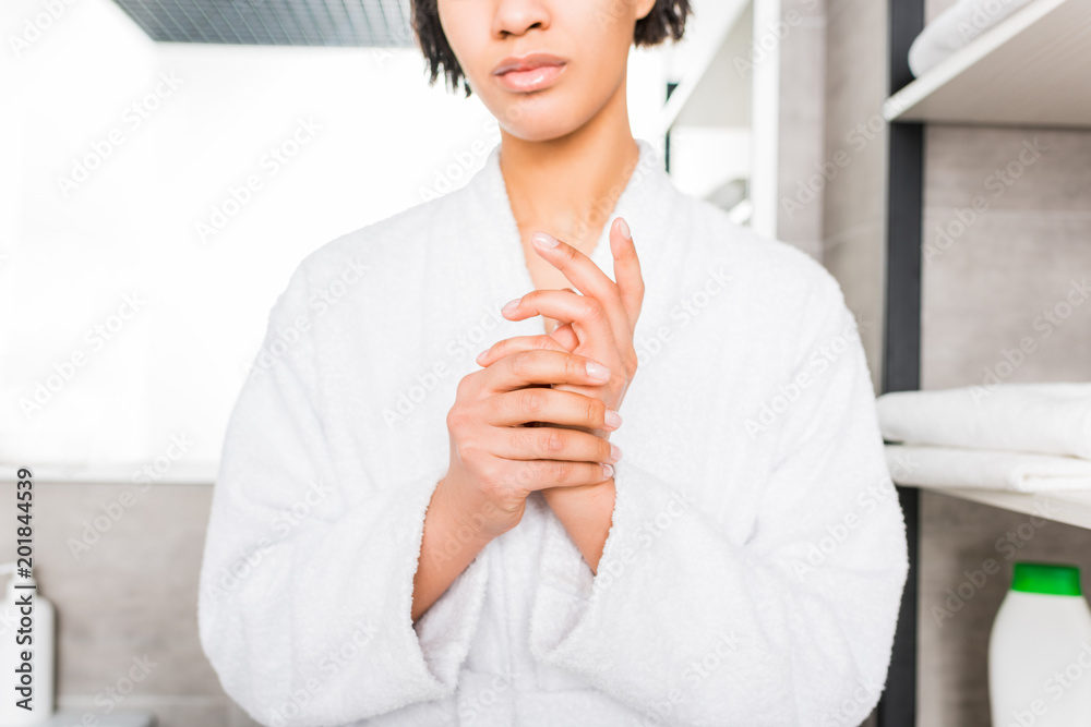 cropped view of african american woman in bathrobe standing in bathroom cropped view of african american woman in bathrobe standing in bathroom