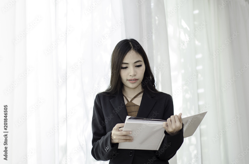 Asian women In black suit Standing holding a white book and smiling happily at work in the morning.Businesswoman standing White background,Black spots on the face of a woman caused by sunlight. Asian women In black suit Standing holding a white book and smiling happily at work in the morning.Businesswoman standing White background,Black spots on the face of a woman caused by sunlight.