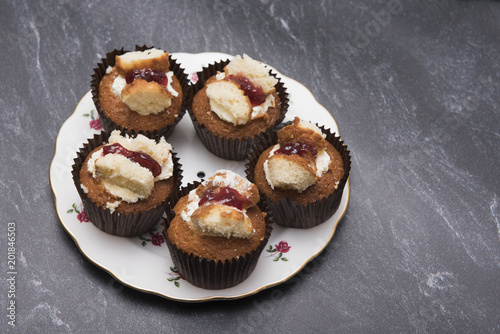 Five raspberry and cream cupcakes on a dark marble background with copy space 