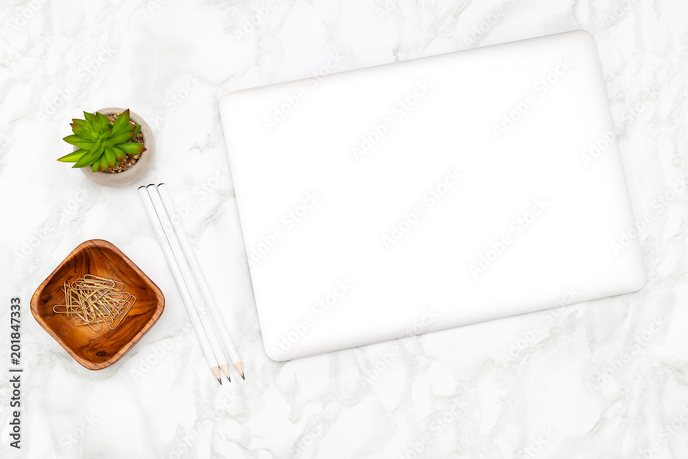 A laptop and paperclips with a pencil on a marble background. Stock