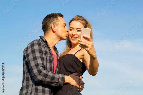 Two Young beautiful man and woman in casual clothes making selfie over blue sky