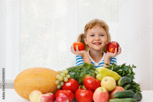 Happy little girl and a lot of fruit and vegetables. 