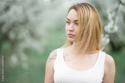 Blonde girl in white dress in blooming spring gardens