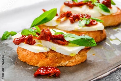 Tasty savory Italian appetizers  or bruschetta  on slices of toasted baguette garnished with basil