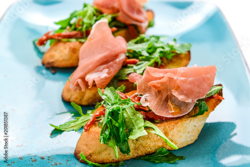 Tasty savory Italian appetizers, or bruschetta, on slices of toasted baguette garnished with basil