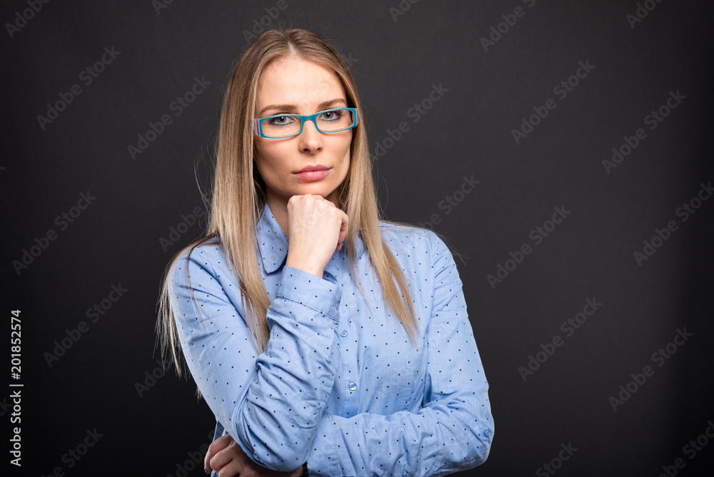Business lady wearing blue glasses posing with hand on chin.