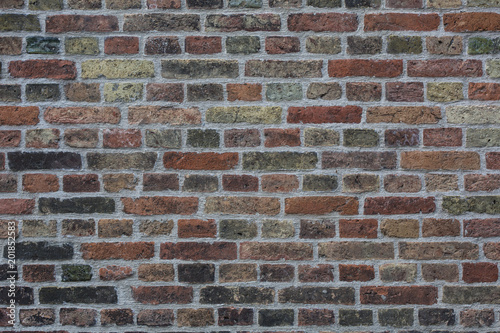 Wall made from red and sometimes colorful bricks of regular shapes and random distribution slotting together precisely. Close up architecture photography. Creative wallpaper photography.