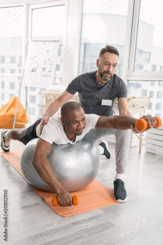 Pleasant workout. Joyful nice positive man smiling while enjoying the physical training photo