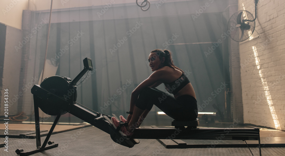 Woman sitting rowing machine at gym Woman sitting rowing machine at gym