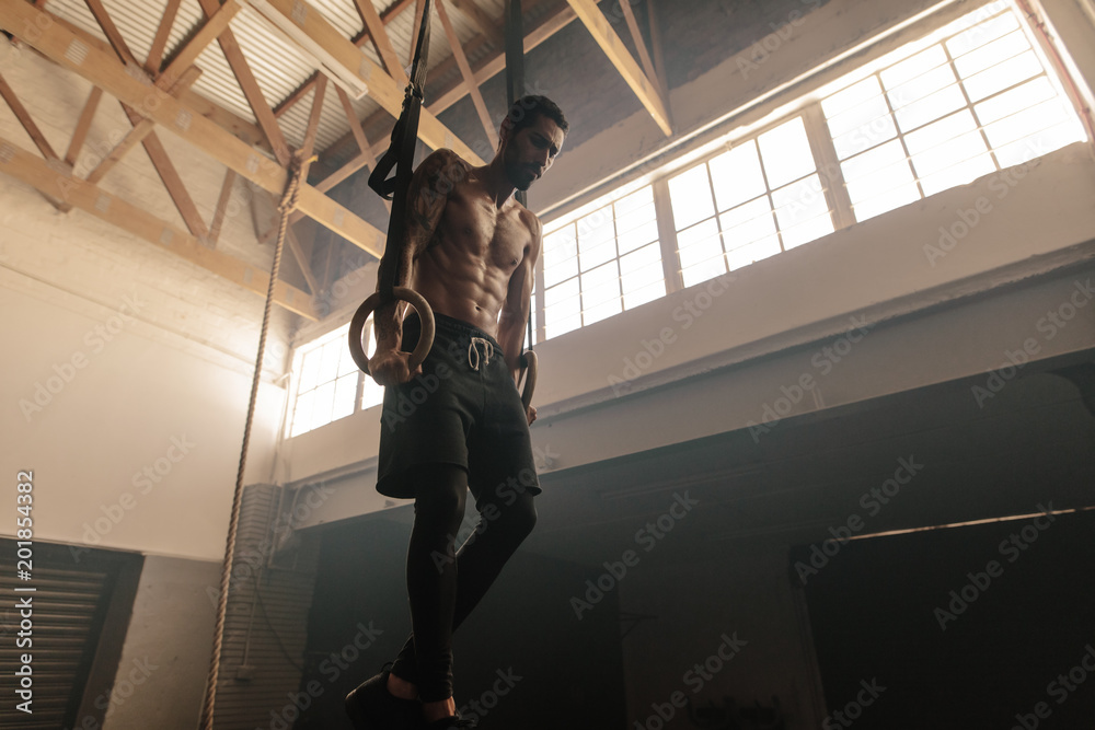 Fototapeta premium Muscular man exercising on gymnastic rings