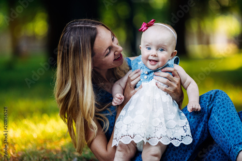 Little baby girl and her mother walking in the park. Blue eyes. Smiling. Teeth