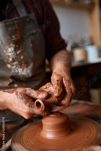 Portrait of a male potter in apron molds bowl from clay, selective focus, close-up photo