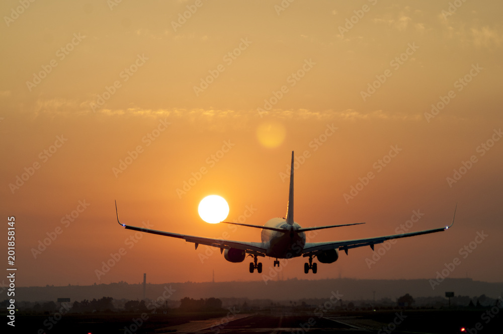 Fototapeta premium Airplane landing at Seville airport at sunset