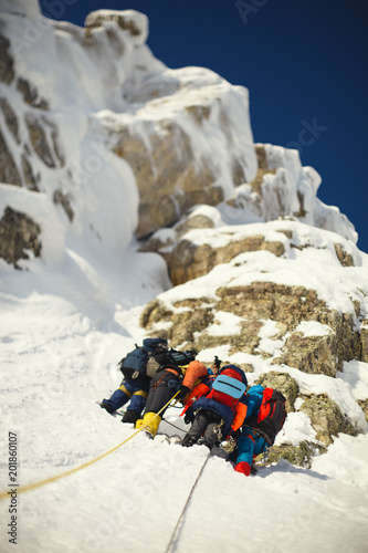 Group mountaineers on a safety enshrined station on the background of snow-covered rocks. Bottom view.  Tilt-shift effect. photo