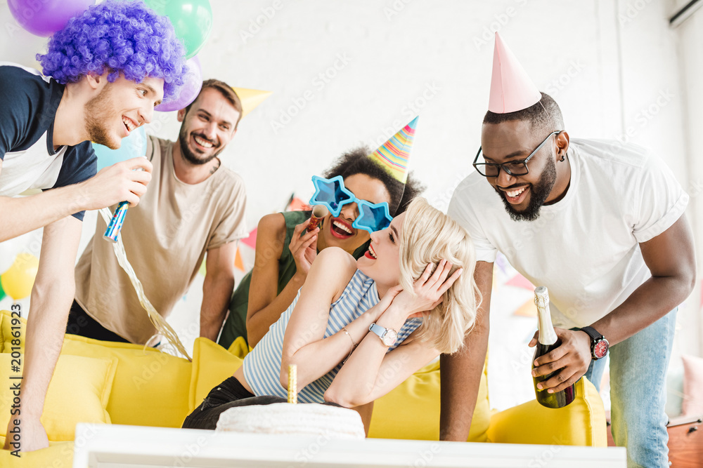 Obraz premium Cheerful friends greeting blonde woman with birthday cake