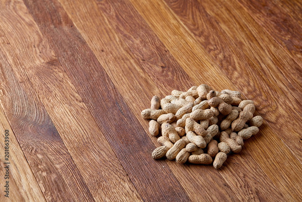 Unpeeled peanuts on a wooden background, top view, selective focus, shallow depth of field. Unpeeled peanuts on a wooden background, top view, selective focus, shallow depth of field.