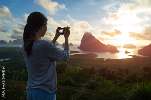 Woman take a photo, sea and mountain with sunrise background. photo