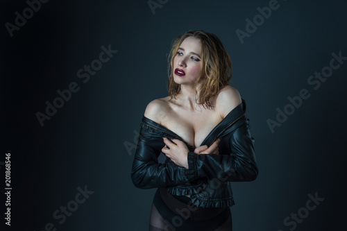 Fashion model wearing leather jacket posing on grey background