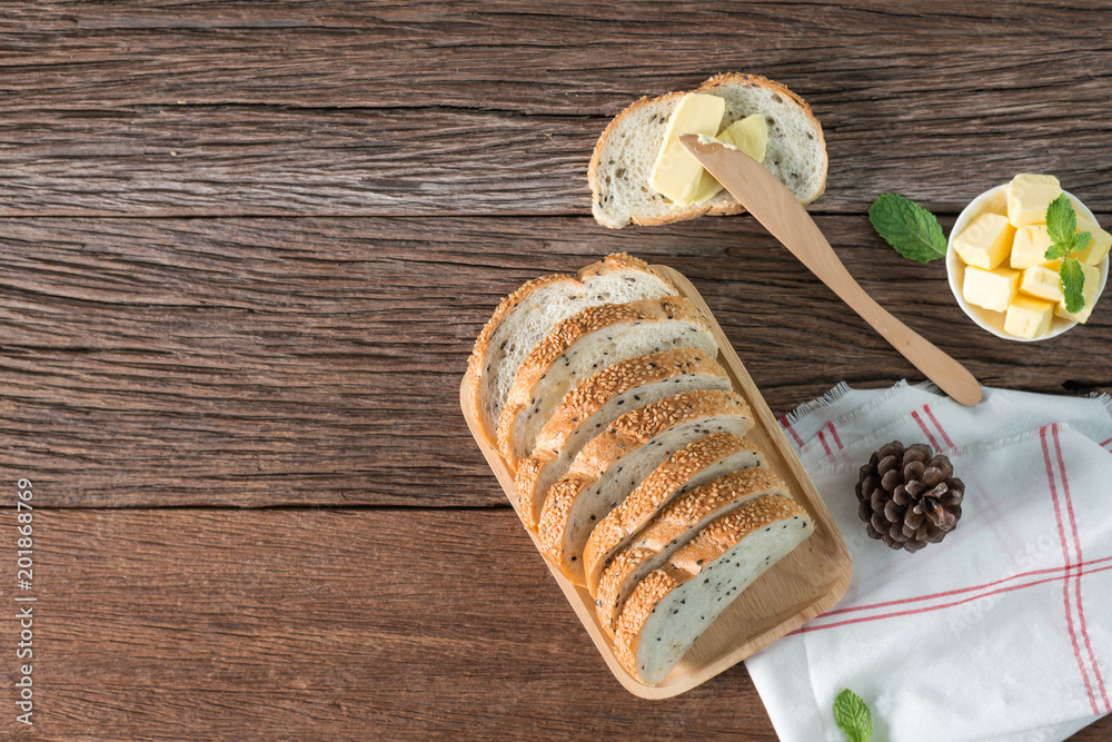 Piece of butter with sesame bread on wood background. Piece of butter with sesame bread on wood background.
