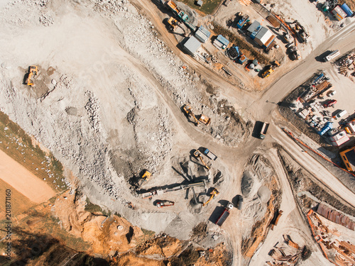 Aerial drone view of excavator loading the tipper truck at the construction site, open pit mine, extractive industry