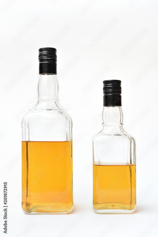 Transparent bottles with alcohol, started. Semi-empty bottles with alcohol on a white background Transparent bottles with alcohol, started. Semi-empty bottles with alcohol on a white background
